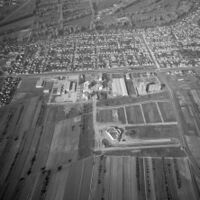 Luftansicht von Neureut, im Vordergrund das neue Zentrum mit der im Bau befindlichen Badnerlandhalle, im Hintergrund das alte Dorf mit den Siedlungserweiterungen der Nachkriegszeit, 1976, Stadtarchiv Karlsruhe 8/BA Schlesiger A26a/139/3/2.